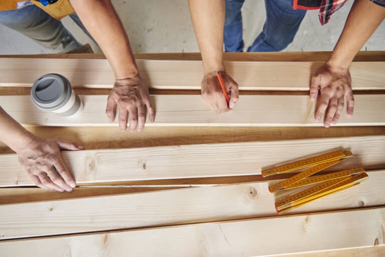 High angle view of two carpenters drawing on wooden planks